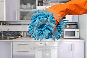 Woman's hand in a protective glove with a rag at the kitchen.