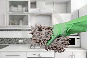 Woman's hand in a protective glove with the rag at the kitchen.