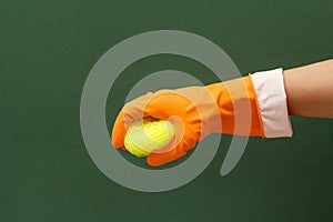 Woman's hand in protective glove with sponge on the green background