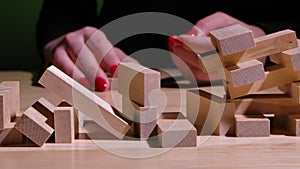 A woman's hand pulls out a wooden brick and the structure collapses. Jenga Tower is hitting the table in slow motion