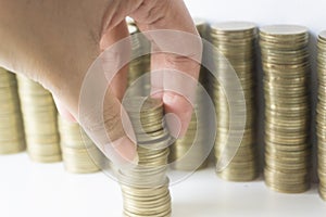Woman`s hand put money coins to stack of coins, Saving money concept