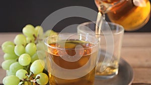 Woman`s hand puts a empty glass in the tray and pouring drink of green grapes