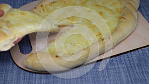 Woman's hand puts  slice of khachapuri back on cutting board