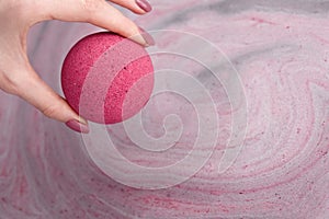 Woman`s hand putting bath bomb into water