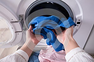Woman`s Hand Putting Blue Cloth Into Washing Machine