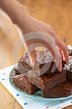 Woman`s Hand Reaching for Homemade Baked Chocolate Brownies