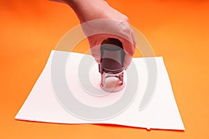 Woman`s hand with the seal, stamp. Process stamping the contract, documents, close up.