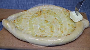 Woman's hand smears  butter khachapuri with fork