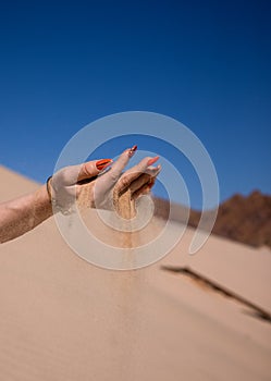 Woman& x27;s hand sows sand on the background of the desert