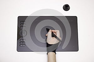A woman`s hand in a special glove draws on a graphic tablet, white background, isolated. Top view, tools for graphic drawing