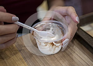 Woman`s hand with spoon and ice cream cup