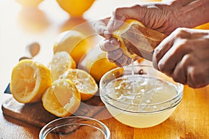 Woman`s hand squeezing juice from a lemon with wooden tool