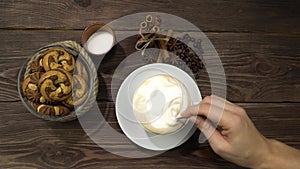 A woman's hand stirring a cappuccino spoon. A lot of milk foam in the drink.