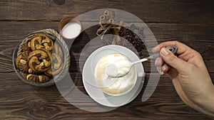 A woman's hand stirring a cappuccino spoon. A lot of milk foam in the drink.