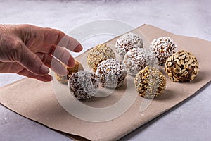 The woman`s hand is stretched to the home energy balls lying on the table on paper.