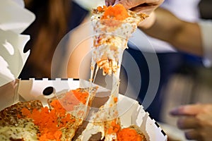 Woman`s hand take pizza pices out from pizza plate in foodtruck event, Cheese`s pizza is stretced by her photo