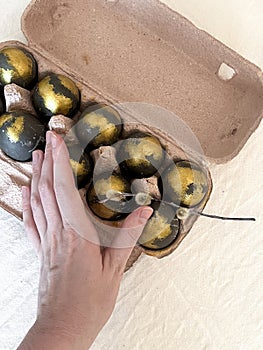 A woman's hand takes an egg from a tray of Easter eggs.