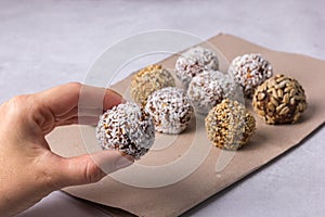The woman`s hand takes from the table a homemade energy ball of dried fruits and nuts