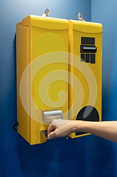 Woman`s hand taking coins from the bill changer machine in yellow color