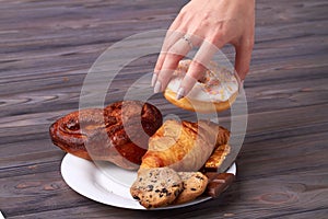 Woman`s hand is taking a delicious donut.