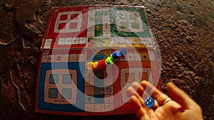 Woman's hand throws dice on field of board game ludo