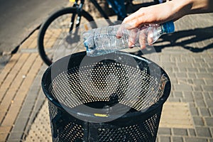 Woman's hand throws empty plastic water bottle