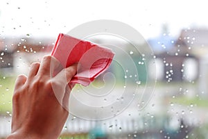 Woman`s hand to wipe drops of water on glass pink fabric. Closeu