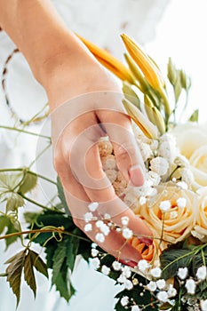 Woman`s hand touches a bouquet of roses and lilies