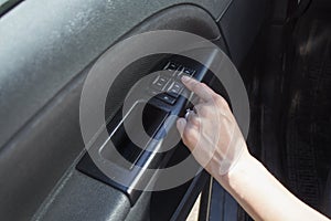 Woman`s hand touches the window adjustment button in the car.