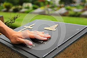 Woman`s hand touching the black stone grave. Sadness moment