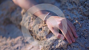 Woman`s hand touching sand on beach