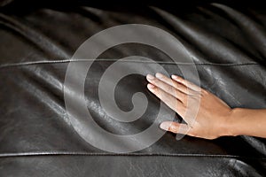 The woman`s hand touching the surface of the sofa.