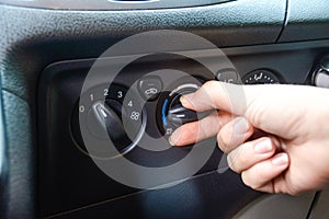 Woman`s hand turning on car air conditioning system