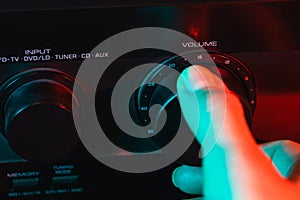 A woman's hand turns on and increases the volume of music on the amplifier. Colorful neon light. Macro