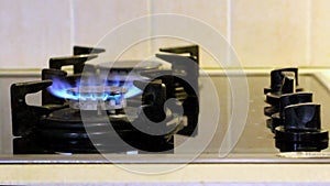 Woman\`s hand turns on kitchen gas burner. Operation burner igniting into blue cooking flame