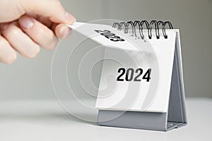 a woman& x27;s hand turns over a calendar sheet. year change from 2023 to 2024