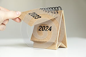 a woman& x27;s hand turns over a calendar sheet. year change from 2023 to 2024.