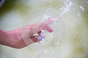 Woman's hand under a stream of water from a fountain