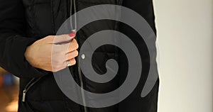 Woman's hand unfasten the zipper on a black jacket