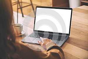 A woman`s hand using and touching on laptop touchpad with blank white desktop screen with coffee cup on wooden