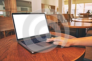 A woman`s hand using and touching on laptop touchpad with blank white desktop screen on wooden table