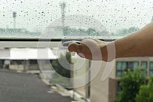 The woman`s hand was closing the window because of the rain photo