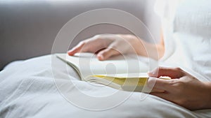 Woman`s hand Who is reading a large book and gradually turning the pages On the sofa