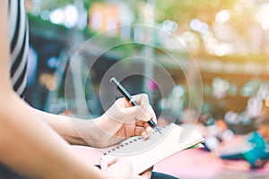 The woman`s hand is writing on a blank notepad