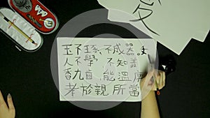 Woman`s hand writing chinese calligraphy. Female hand holding a writing brush Chinese characters