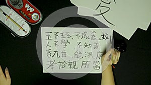 Woman`s hand writing chinese calligraphy. Female hand holding a writing brush Chinese characters