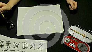 Woman`s hand writing chinese calligraphy. Female hand holding a writing brush Chinese characters