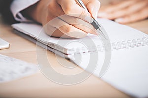 Woman's hand writing in notepad