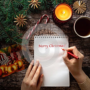 Woman's hand writing on a notepad sheet in Christmas setting