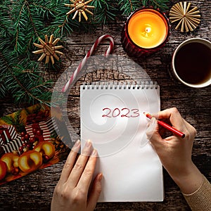 Woman's hand writing on a notepad sheet in winter holiday setting